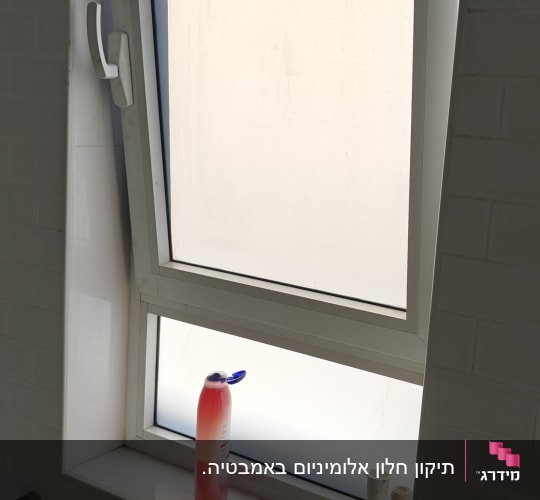 חלון עם תריסים פתוחים למחצה בחדר אמבטיה